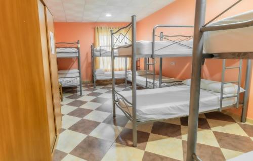Pokój z 3 łóżkami piętrowymi i podłogą wyłożoną szachownicą w obiekcie Albergue Rojo Plata w mieście Torremegía