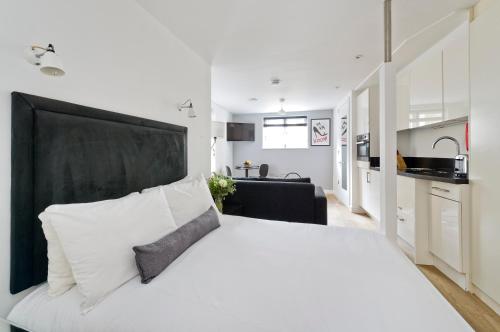 a bedroom with a large white bed with a black headboard at Crane Court by City2Stay in London