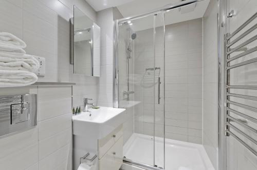 a white bathroom with a shower and a sink at Crane Court by City2Stay in London