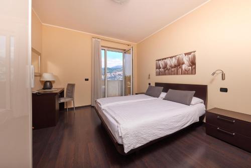 a bedroom with a bed and a desk and a window at Hotel Villa Smeralda in Malcesine
