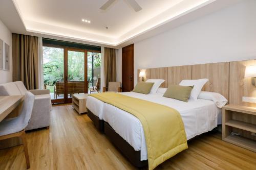 a hotel room with a large bed and a desk at PortBlue Club Pollentia Resort & Spa in Alcudia