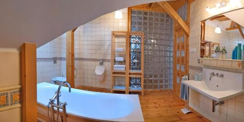La salle de bains est pourvue d'une baignoire, d'un lavabo et d'un miroir. dans l'établissement Apartmán Brasserie Avion, à Rožnov pod Radhoštěm