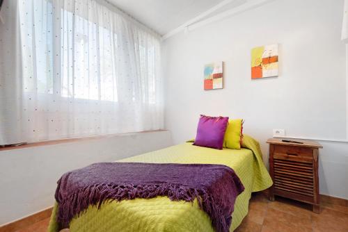 1 dormitorio con 1 cama con manta morada y amarilla en Residencial Primavera, en Arona