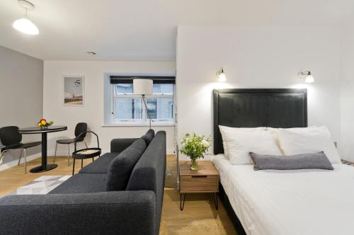 a bedroom with a bed and a couch and a table at Crane Court by City2Stay in London