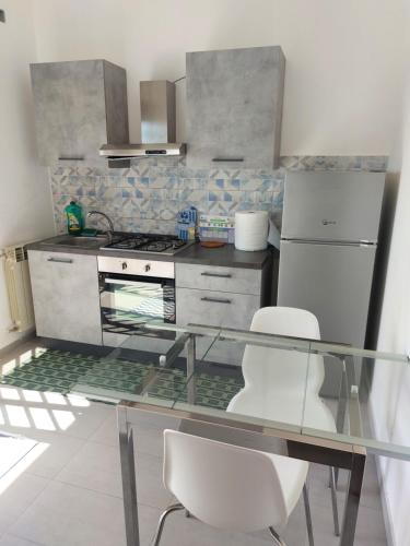 a kitchen with a glass table and white chairs at Casa Arrigo in Catania