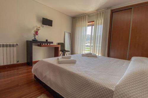 um quarto com uma cama grande com duas toalhas em Casa das Estrelas em Braga