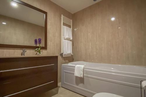 a bathroom with a tub and a sink and a mirror at Casa das Estrelas in Braga