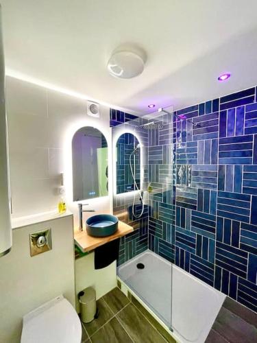 La salle de bains est pourvue de toilettes et d'une douche avec du carrelage bleu. dans l'établissement Appartement en résidence calme / Puteaux - La Défense, à Puteaux