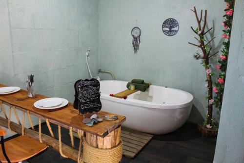 a bathroom with a white bath tub and a wooden table at Vila Ecológica Cambará in Cambará