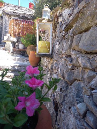 a stone wall with a window and purple flowers at Alexadras Guesthouse in Ampelochórion