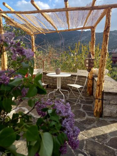 a patio with a table and purple flowers at Alexadras Guesthouse in Ampelochórion