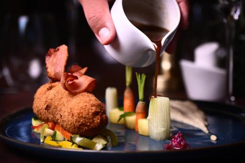 a person is pouring sauce onto a plate of food at ibis Styles Dijon Sud Domaine De Beauregard 21600 Longvic in Longvic