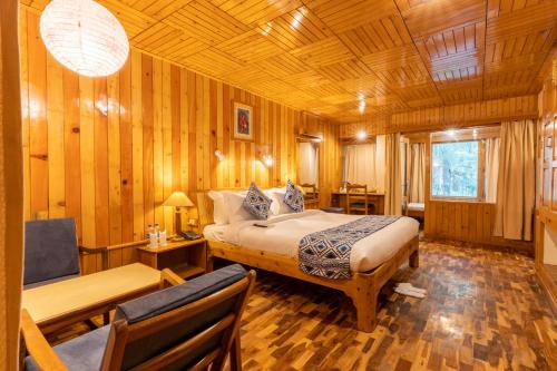 a bedroom with a bed and a table and chairs at Hotel Negi's Mayflower A heritage Since 1965 in Manāli