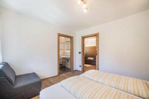 a bedroom with a bed and a chair and a mirror at Ferienwohnung Lazins in Pfelders