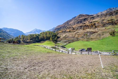 a fence in a field with mountains in the background at Ferienwohnung Lazins in Pfelders