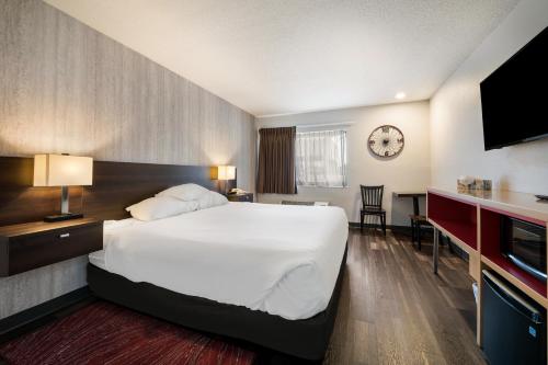 a hotel room with a bed and a clock on the wall at Red Lion Inn & Suites Ontario in Ontario