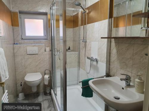 La salle de bains est pourvue d'une douche, d'un lavabo et de toilettes. dans l'établissement Ferienwohnung Waldgarten, à Bad Münstereifel