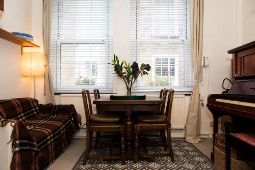 a living room with a table and a piano at Hampstead 19th Century Village Cottage in London