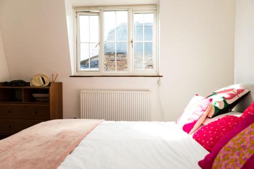 a bedroom with a bed and a window at Hampstead 19th Century Village Cottage in London