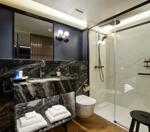 a bathroom with a shower and a sink and a toilet at Hotel SANSEbay in Donostia-San Sebastián