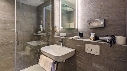 La salle de bains est pourvue d'un lavabo et d'une douche. dans l'établissement Hotel Strandhotel, à Iseltwald