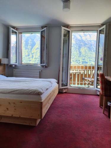 um quarto com uma cama e 2 janelas grandes em Hotel Strandhotel em Iseltwald
