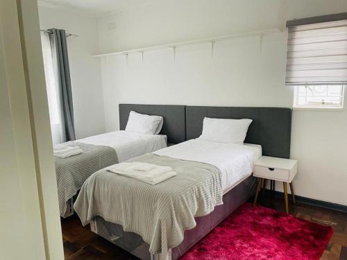 布拉瓦約的住宿－Remarkable 2-Bed House in Bulawayo，红色地毯小客房内的两张床