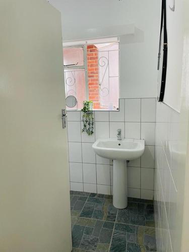 a white bathroom with a sink and a window at Bulawayo Bradfield Retreat - 3 Bed House in Bulawayo