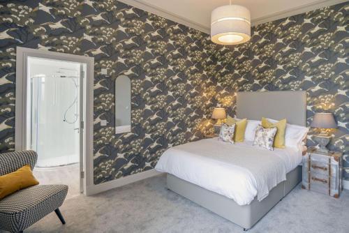 a bedroom with a bed and a wall with bird wallpaper at The Woodside in Doune