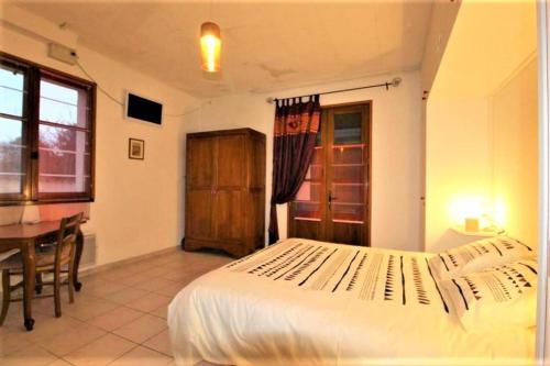 a bedroom with a bed and a table and a window at Gîte et chambre d'hôtes LE MERCOIRE, piscine chauffée et jacuzzi in Aubenas