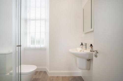 a white bathroom with a toilet and a sink at The Woodside in Doune