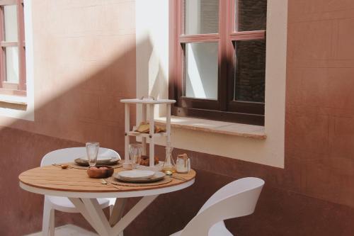 a table with two white chairs and a window at Hotel Palau Macelli in Castell&oacute; d'Emp&uacute;ries