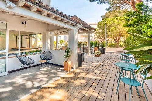 una terraza de madera con sillas y mesas en una casa en L'Oasis Hotel en Fréjus