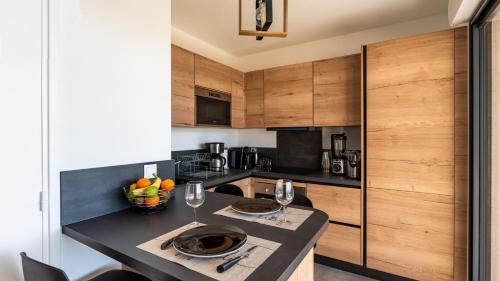 a kitchen with wooden cabinets and a table with wine glasses at Les Rivages de Stagnola Appartement T3 vue mer et montagne plage 200m climatisé in Pietrosella