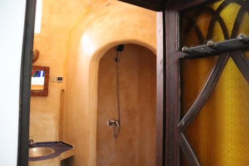 a door to a bathroom with a sink and a toilet at Hotel Dar El Qdima in Essaouira
