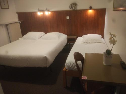 a hotel room with two beds and a table at Le Nouveau Monde in Breuillet