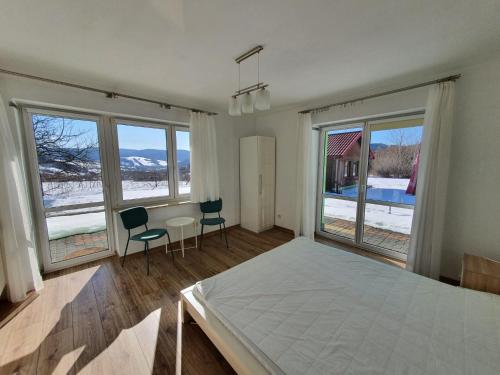 a bedroom with a bed and two chairs and windows at Apartament Tadeusz 2 B in Krynica Zdrój