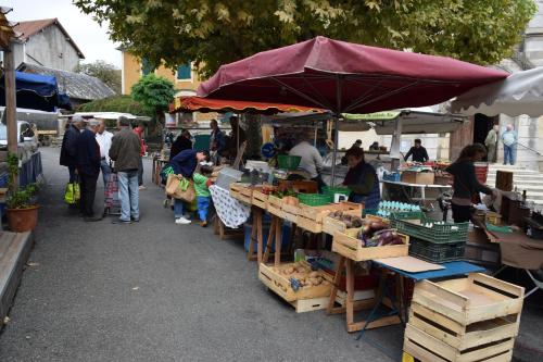 a group of people standing at an outdoor market at location maison à Cajarc 46160 (Lot) in Cajarc
