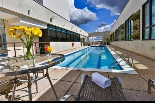 a pool with a glass table and chairs next to a building at Flat 1015 - Comfort Hotel Taguatinga in Brasilia