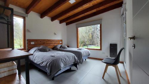 a bedroom with two beds and a desk and a chair at Alojamiento Chacra El Monje in El Hoyo