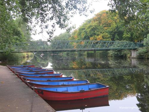 a row of boats sitting in the water under a bridge at Clock Tower Flats Morpeth in Morpeth