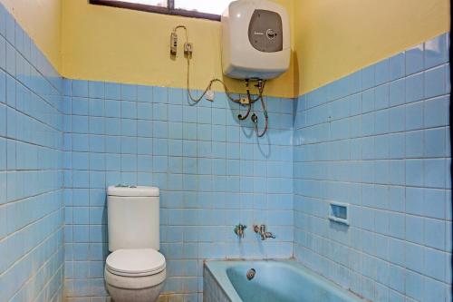 a blue tiled bathroom with a toilet and a bath tub at SPOT ON 91798 Hotel Grand Mutiara in Cikampek
