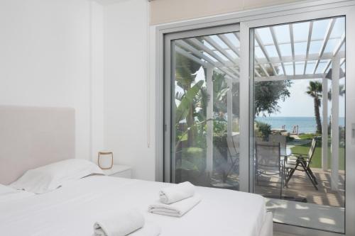 een witte slaapkamer met uitzicht op de oceaan bij The MedView Garden House in Perivolia