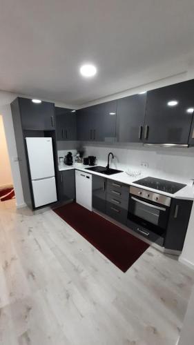 a kitchen with black cabinets and a sink and a refrigerator at Apartamento da Antónia in Viseu