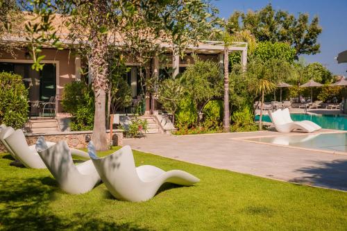 a group of white chairs on the grass near a pool at Daluz Boutique Hotel in Preveza