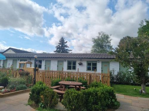 a house with a wooden fence and a picnic table at Pine, Country chalet located in Pegsdon in Hexton