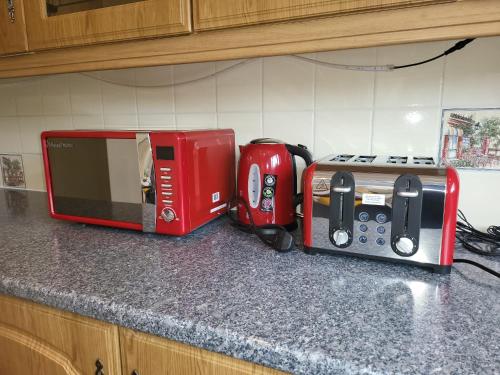 a kitchen counter with a red microwave and a toaster at Spacious serviced home with free parking & Wi-Fi in Willenhall