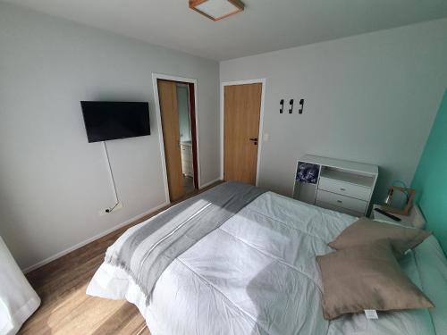 a bedroom with a large bed and a flat screen tv at Hygge Haus in Villa La Angostura