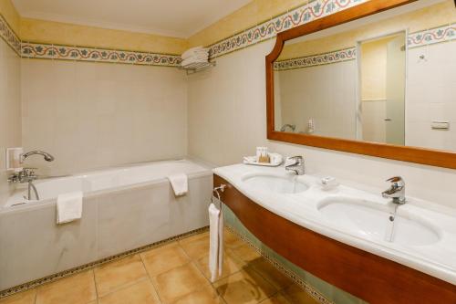 a bathroom with two sinks and a tub and a mirror at La Quinta Menorca by PortBlue Boutique - Adults Only in Cala en Bosc