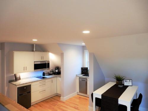 a small kitchen with white cabinets and a table at The Loft in Lyndeborough